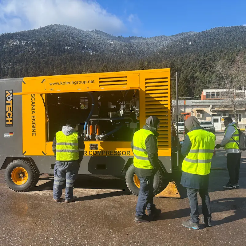 Kotech KDP-30/25 diesel portable air compressor operating alongside a DTH drilling rig at an open-pit iron ore mine in South Africa.